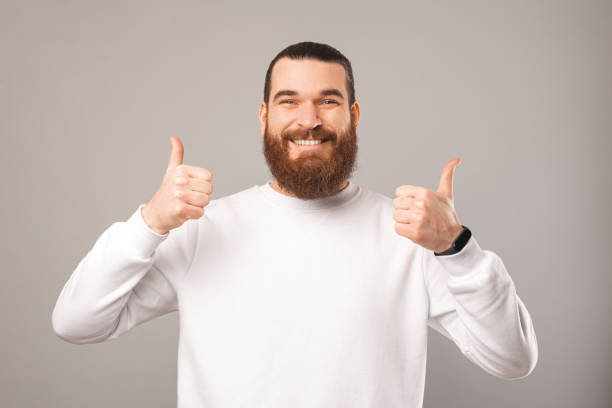 istock Friendly bearded man is showing two thumbs up while smiling at the camera. 1396637856