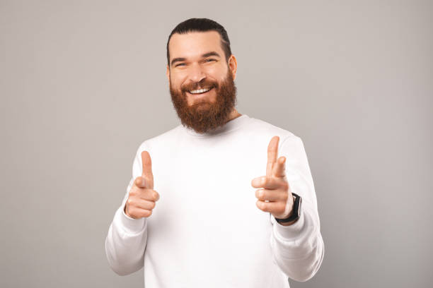istock Smiling young man is pointing towards the camera for you in a studio. 1396637928