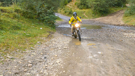 Biker fords stream. Carpathian Mountains
