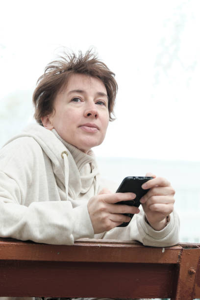 istock Mature woman is using phone while sitting on street bench 1396641938