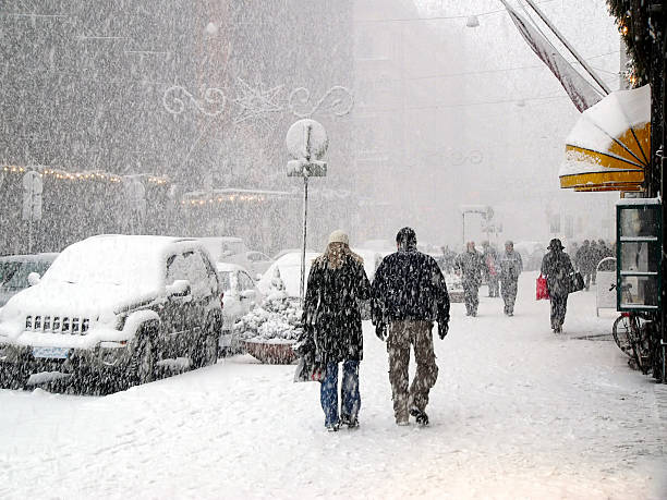 Pedestrians in the city during a severe blizzard. Persons crossing the street, snow storm. Focus on foreground snowflakes