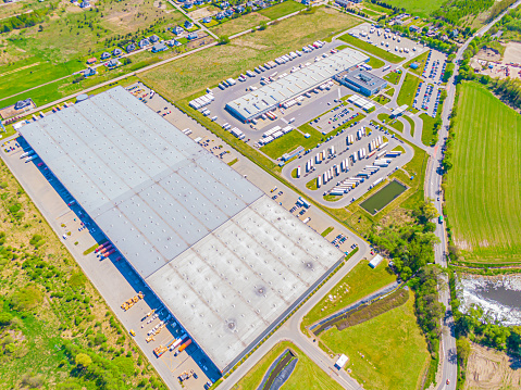Aerial view of goods warehouse. Logistics center in industrial city zone from above. Aerial view of trucks loading at logistic center