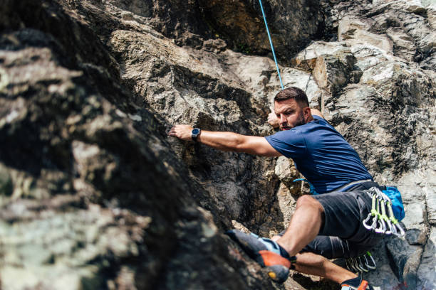 istock Strong man looking focused, using all his strength, climbing on the rock. 1396642360