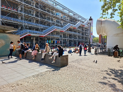 The Centre Pompidouwas designed in the style of high-tech architecture by the architectural team of Richard Rogers, Su Rogers, Renzo Piano and realized between 1971 and 1977. The Museum contains the Musée National d'Art Moderne, which is the largest museum for modern art in Europe. The image shows the museum during springtime with several people in front of the mai n Entrance.