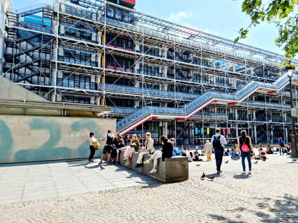 Centre Pompidou with people in front of the musuem The Centre Pompidouwas designed in the style of high-tech architecture by the architectural team of Richard Rogers, Su Rogers, Renzo Piano and realized between 1971 and 1977. The Museum contains the Musée National d'Art Moderne, which is the largest museum for modern art in Europe. The image shows the museum during springtime with several people in front of the mai n Entrance. pompidou center stock pictures, royalty-free photos & images