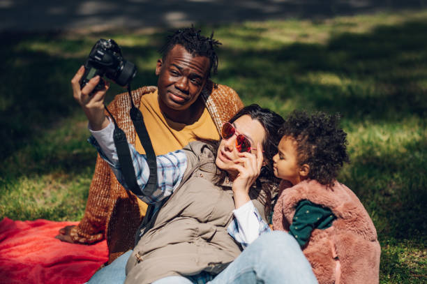 istock Beautiful multiracial family using a digital camera in the park. 1396643467