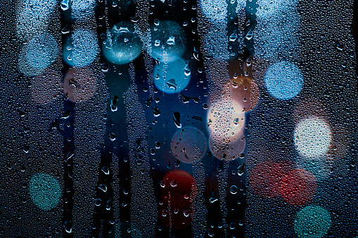 drops on the window and street lights at night background