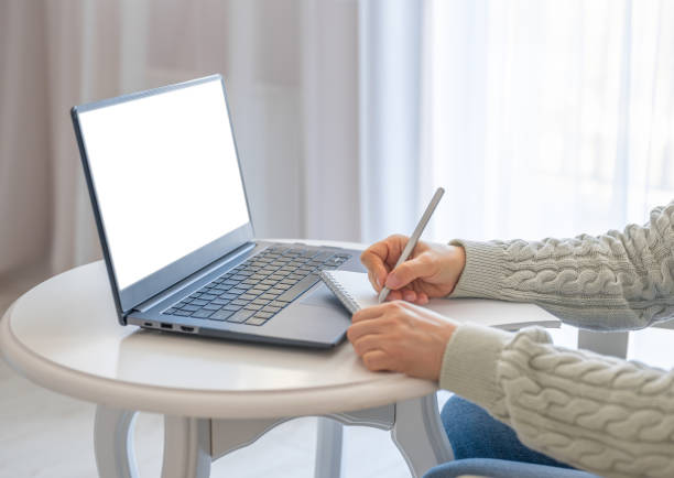 vista laterale e primo piano delle mani della donna utilizzando il laptop con schermo bianco vuoto e scrittura nel blocco note. mockup laptop. mani al lavoro con la tecnologia digitale - personal organizer meeting business cyberspace foto e immagini stock