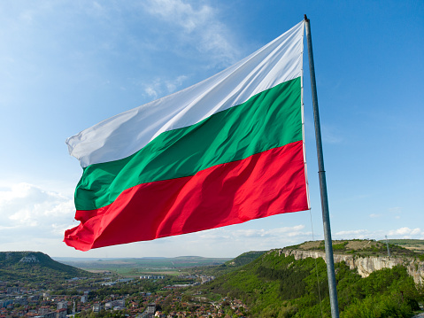 Bulgaria National Flag Waving on pole against sunny blue sky background.