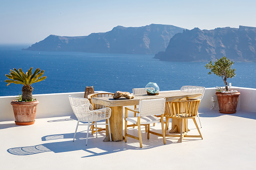 A sun terrace for rest with a wooden table and chairs in Thira, Santorini island, Greece.