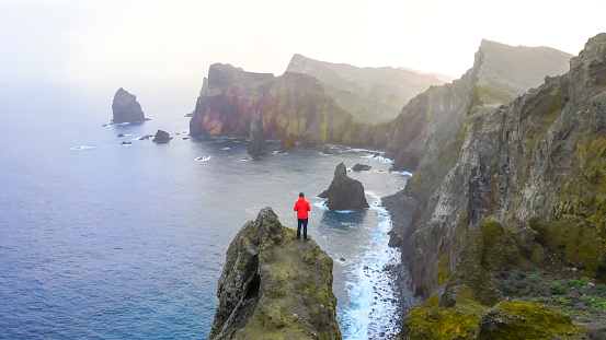 He stands on elevated rocky cliff, in Madeira