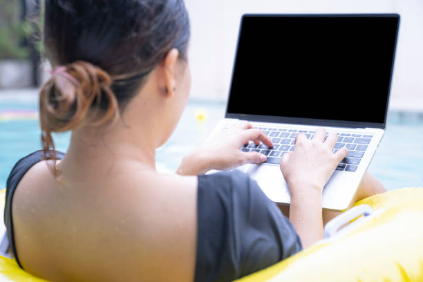 Freelancer women working on vacation, Young woman typing on computer laptop while sitting on rubber ring in the pool. Work from anywhere, freelance.