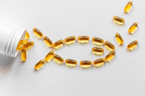 capsules with fish oil from cod liver in the shape of a fish on a white background