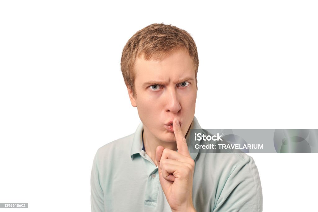 Funny guy in light gray Polo T-shirt asking to be quiet, silence gesture, white background Funny guy in light gray Polo T-shirt asking to be quiet, silence gesture isolated on white background. Young man saying Shhh, keep quiet, please and making silence gesture, request for silence 25-29 Years Stock Photo