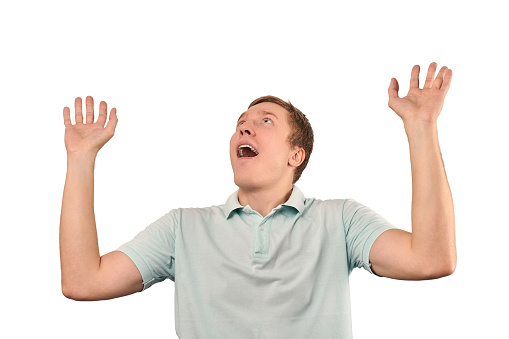 Funny smiling man in green T-shirt showing palms of hands and looking up, unexpected surprise gesture isolated on white background. Attractive happy man hearing good news, catching something