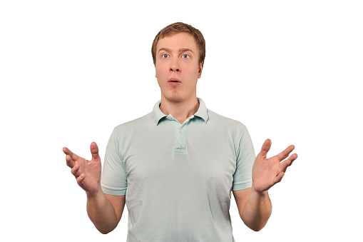 Confused young guy shrugged shoulders, guy in mint casual T-shirt spread arms, isolated on white background. Puzzled young man spread his hands, bewildered don't know gesture