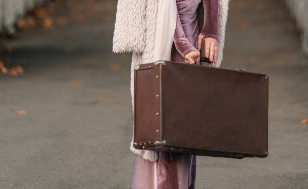 belle fille élégante tient une vieille valise vintage dans ses mains. concept de voyage. migrants forcés ukrainiens. rechercher un logement et travailler dans un autre pays pour les expatriés. - suitcase retro revival women old fashioned photos et images de collection