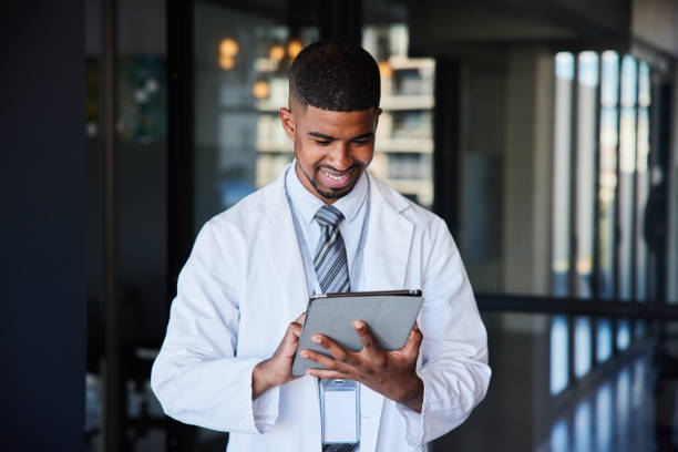 istock Smiling young male doctor using a tablet in a hospital hall 1396649168