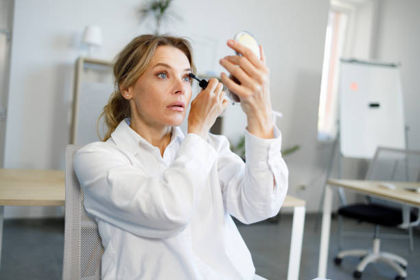 istock Elegant female office worker doing makeup using mascara at workplace 1396651854
