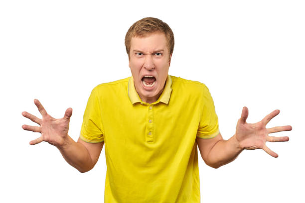 Angry young man in yellow T-shirt spread his hands and yelling isolated on white background Angry guy in yellow T-shirt spread his hands and yelling isolated on white background. Yelling man in bright yellow T-shirt very angry and annoyed, relationship conflict, quarrel concept domestic violence india stock pictures, royalty-free photos & images