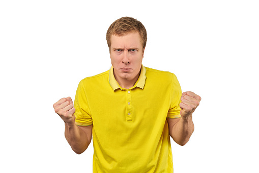 Angry guy in yellow Polo T-shirt spread his hands and ready to fight isolated on white background. Unhappy man in yellow T-shirt very disgruntled and annoyed, relationship conflict, quarrel concept