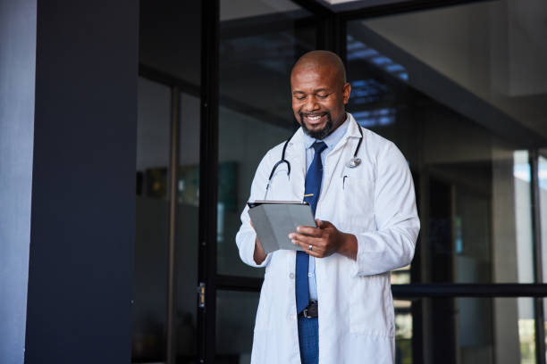 istock Mature male doctor smiling while using a digital tablet in a hospital 1396653690