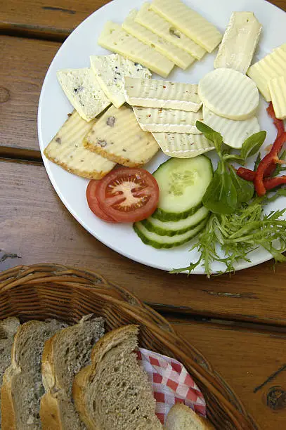 Cheeseplate with bread on wooden table                                