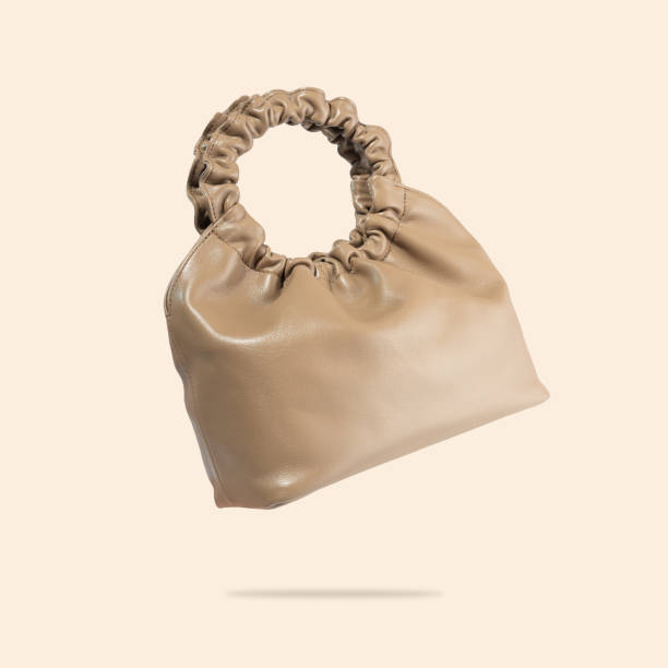 istock A brown eco-leather bag flyies on a beige background. A creative composition of a floating handbag. A conceptual composition of fashionable women's accessories. Handmade vegan friendly leather bag 1396661148