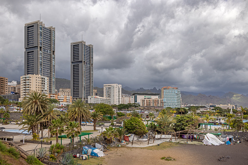 High rise buildings with a tent camp for homeless people in the front at the coast outside Santa Cruz which is the main city on the Spanish Canary Island Tenerife