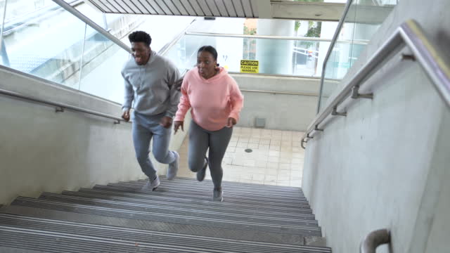 African-American couple running up steep concrete stairs