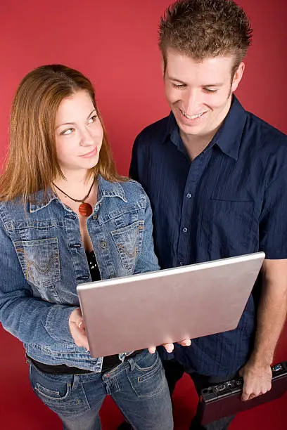 Two young adults, male and female, comparing information on laptops, she is obviously right.