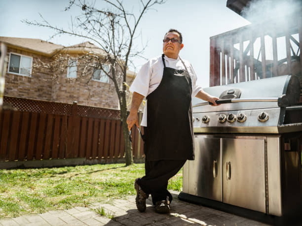 Mature Latin Chef posing by the backyard BBQ stock photo