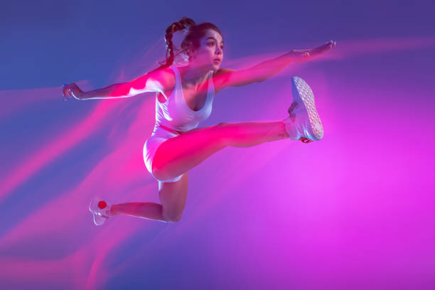 Cheerful young woman having fun on roof balcony, jumping, at night.