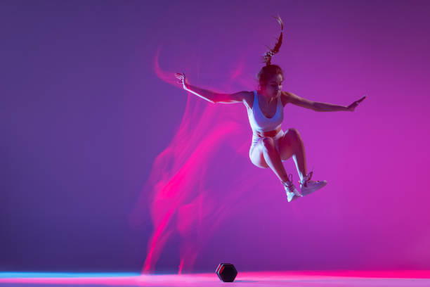 istock Young girl, athlete training isolated on blue studio background in mixed pink neon light. Healthy lifestyle, sport, motion and action concept. 1396668614