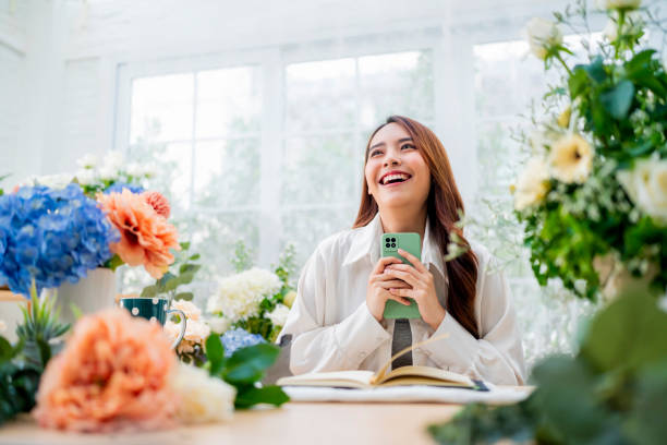 tomando orden florista trabajando desde casa, joven florista asiático haciendo lista de pedido del cliente para organizar la entrega de jarrones de bouqet de flores, tienda de diseño de flores. felicidad joven sonriente haciendo florero - florist women bouquet spring fotografías e imágenes de stock