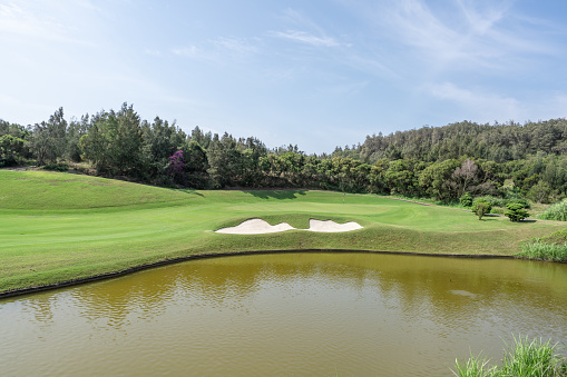 Golf course panorama at sunset with beautiful sky. Scenic panoramic view. Golf course with pine trees.