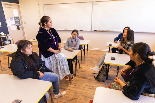 A Navajo woman and high school teacher teaches math to her students in a classroom. Image taken on the Navajo Reservation, Utah, USA.