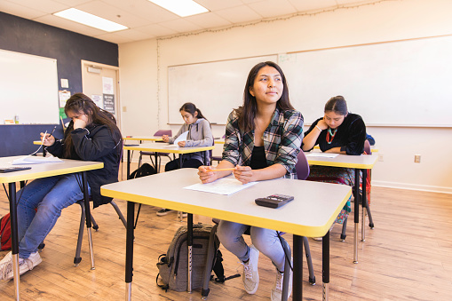 A Navajo female high school student takes a test in math class. She is confident in her education. Image taken on the Navajo Reservation, Utah, USA.