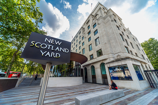 London,England,United Kingdom-August 21 2019: Headquarters of the Metropolitan Police Service,with it's iconic rotating sign,stands opposite the London Eye,in Westminster,on a warm summer afternoon.