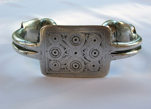 A beautiful close-up of a silver toned bracelet on a stone decorated with dry leaves