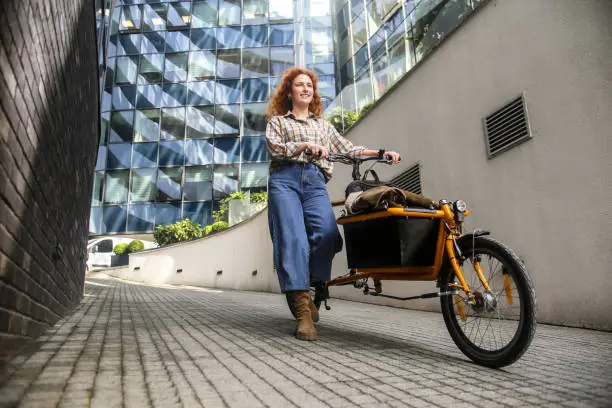 Young woman riding a cargo bicycle. About 25 years old, Caucasian redhead.