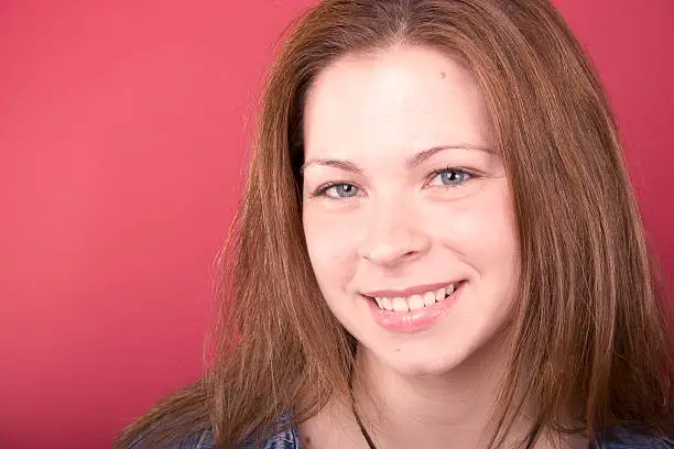 A smiling Young Adult female on a red background.