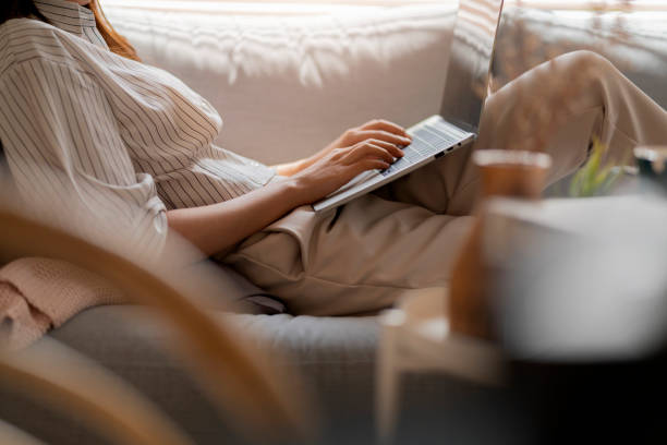 istock young attractive asian female working at home hand use laptop checking search schedule working process planning report with leisure relax on sofa in living room with morning light peaceful moment 1396678532