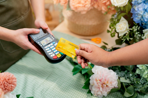 Close up of easy payment by credit card or smartphone application Greenhouse workers selling pottered flowers.Contactless payment with credit card customer at counter using QR code contactless payment