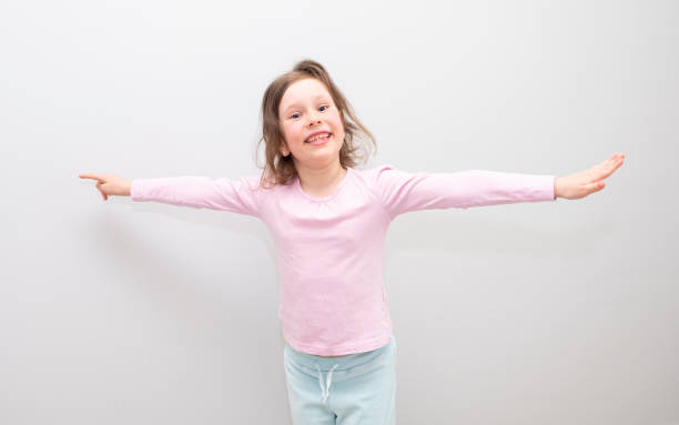 emociones en la cara y gestos con las manos. la niña está feliz, sonríe y extiende los brazos hacia un lado. retrato de una niña caucásica de 6 años, espacio para copia. - cute light skin girls fotografías e imágenes de stock