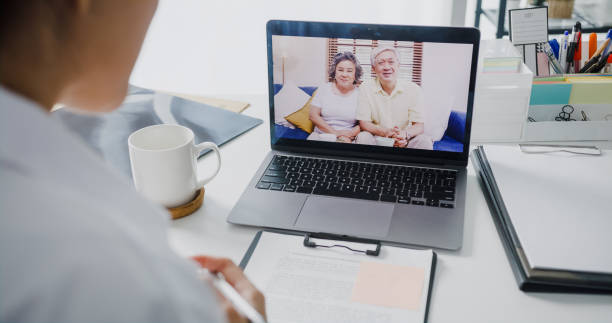istock Young Asia lady doctor in white medical uniform with stethoscope using computer laptop talking video conference call with patient at desk in health clinic or hospital. 1396680383