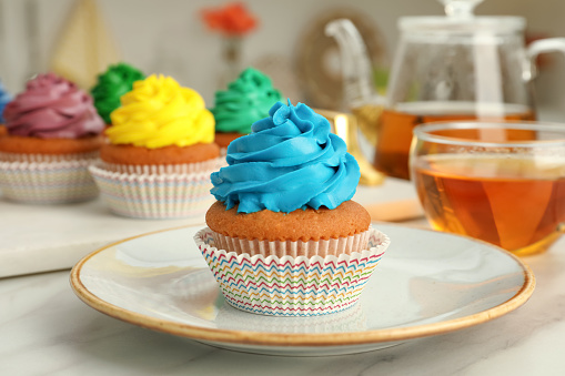 Delicious cupcake with light blue cream on white table
