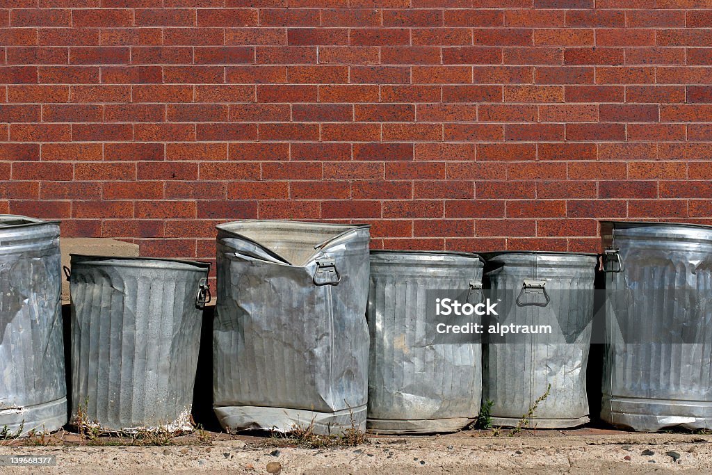 Banged up metal trash cans in an urban setting line of metal trash cans against a red brick wall Garbage Can Stock Photo