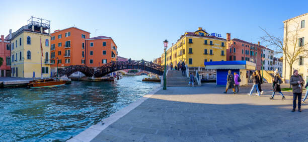 Venice, Italy - March 01, 2022: Panoramic view of the Rio Novo Canal, with buildings, bridges, boats, locals, and visitors, in Venice, Veneto, Northern Italy