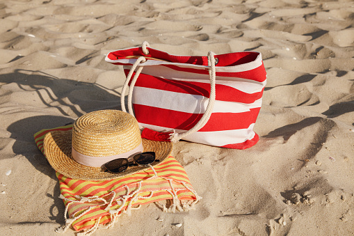 Beach bag, towel, straw hat and sunglasses on sand